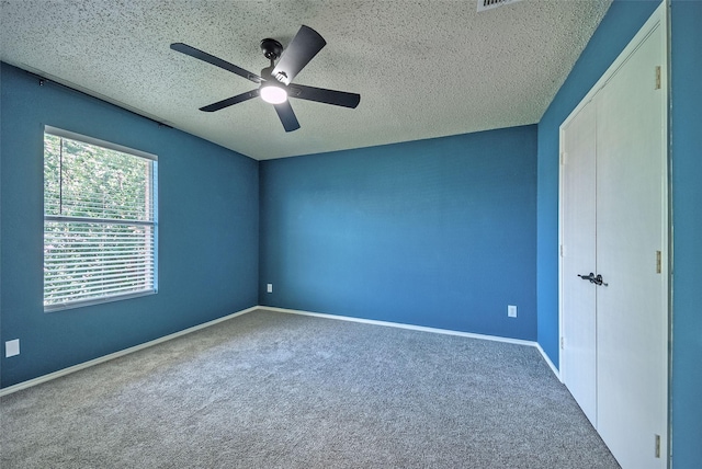 unfurnished bedroom featuring a textured ceiling, carpet flooring, a ceiling fan, and baseboards