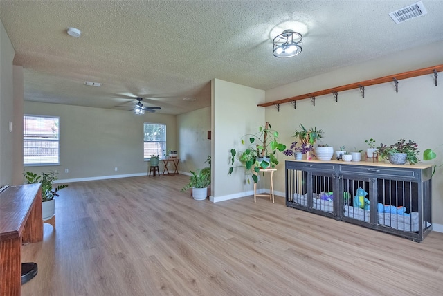 interior space featuring visible vents, a ceiling fan, a textured ceiling, wood finished floors, and baseboards