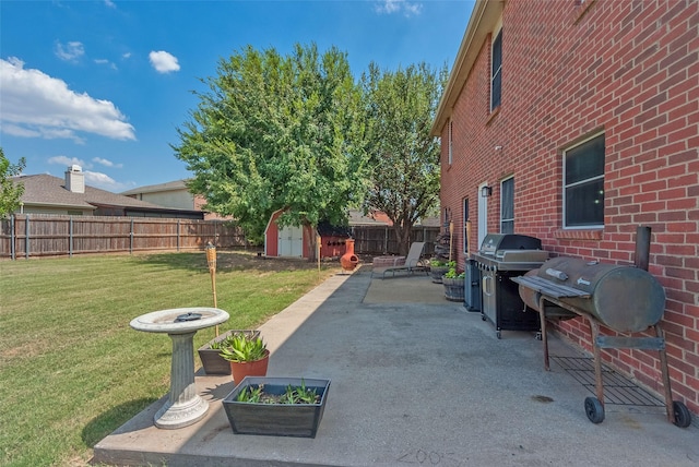 view of yard with a fenced backyard, a patio, an outdoor structure, and a storage unit