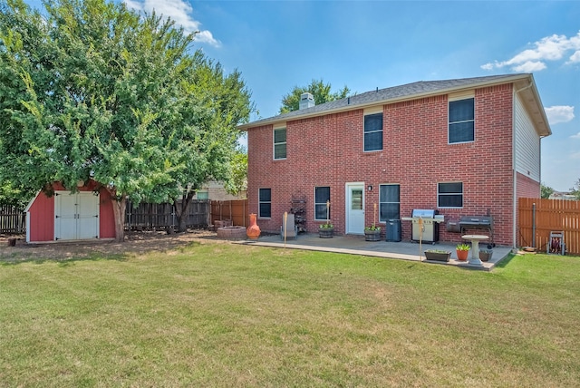 back of house with a patio, a fenced backyard, a storage shed, brick siding, and a yard