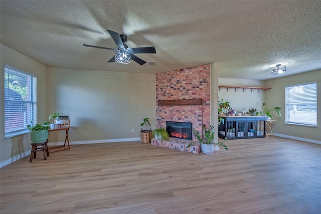 living area featuring a brick fireplace, wood finished floors, and a wealth of natural light