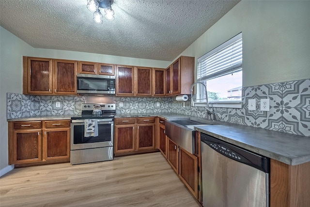 kitchen featuring brown cabinetry, stainless steel appliances, a sink, and light wood finished floors