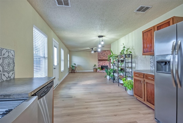 kitchen featuring light wood-type flooring, visible vents, a fireplace, and appliances with stainless steel finishes