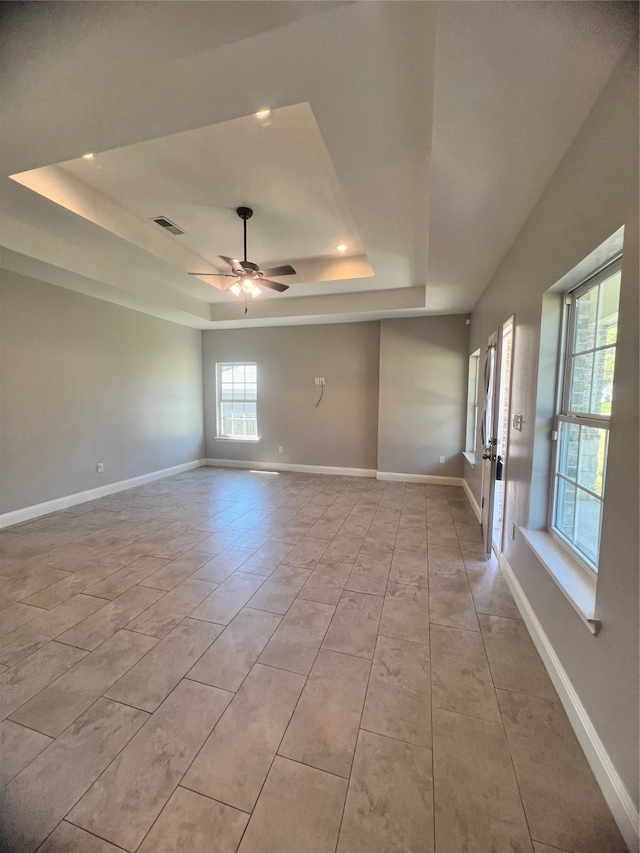 tiled spare room with a raised ceiling and ceiling fan