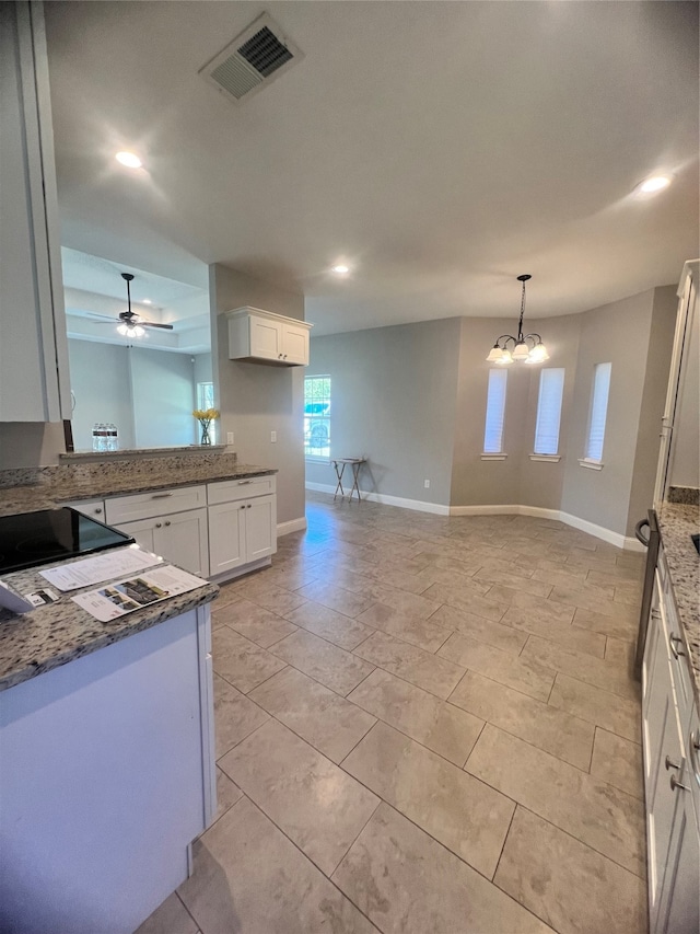 unfurnished living room with a raised ceiling, plenty of natural light, and ceiling fan