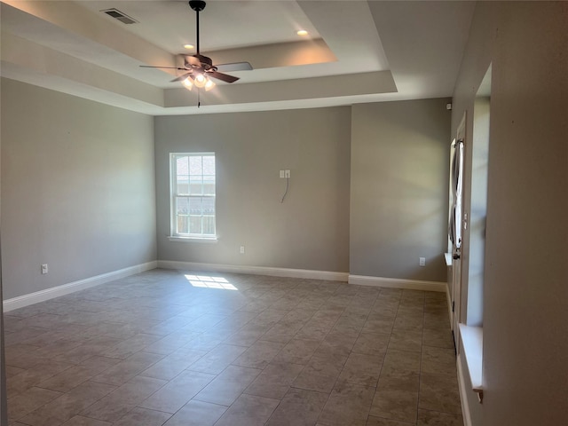 unfurnished room with ceiling fan and a raised ceiling