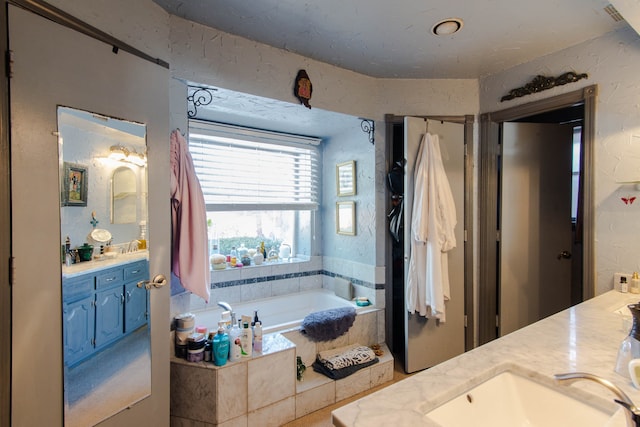 bathroom with tiled tub and vanity