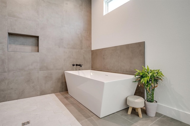 bathroom featuring tile walls, tile patterned floors, and a bathtub