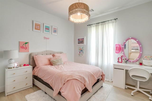 bedroom with a notable chandelier, light wood-style floors, and visible vents