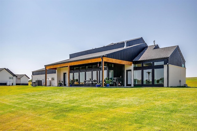 back of house featuring a yard, board and batten siding, and a patio area