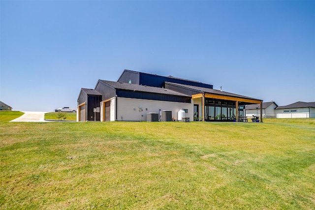 rear view of house featuring central AC and a lawn