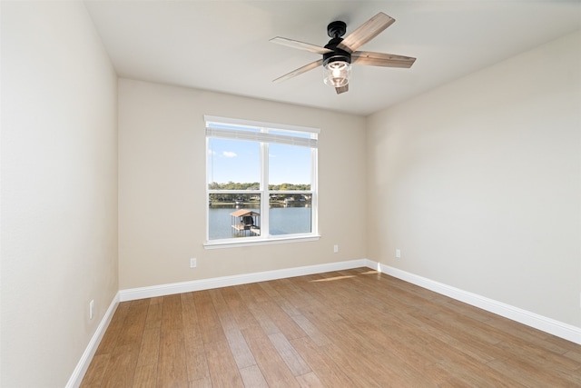 unfurnished room with wood-type flooring, a water view, and ceiling fan