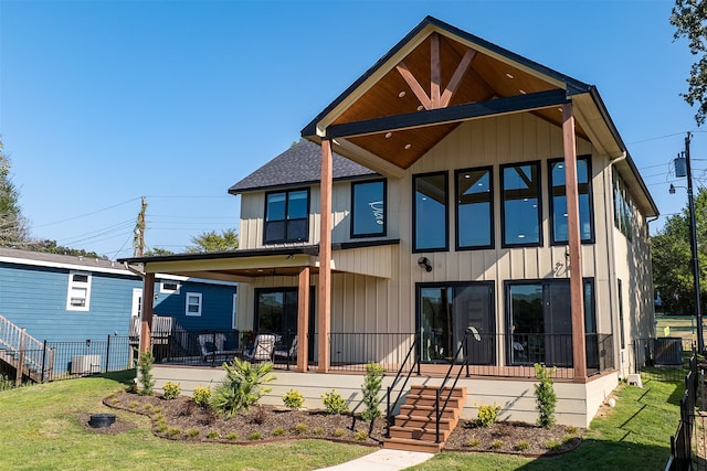 back of property with a lawn and covered porch