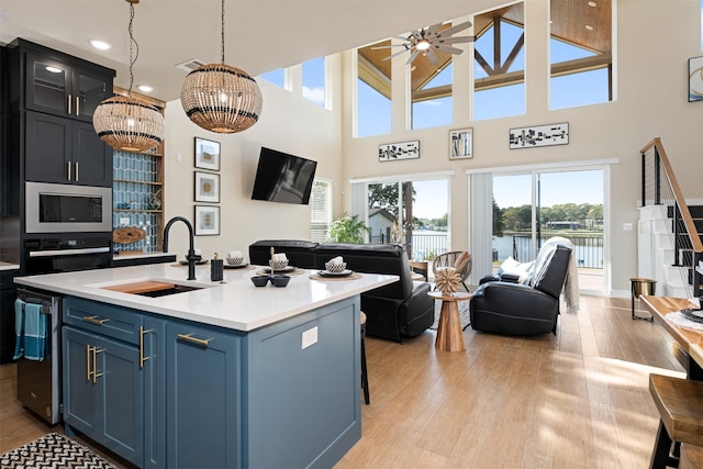 kitchen featuring black oven, sink, blue cabinets, a chandelier, and a kitchen island with sink