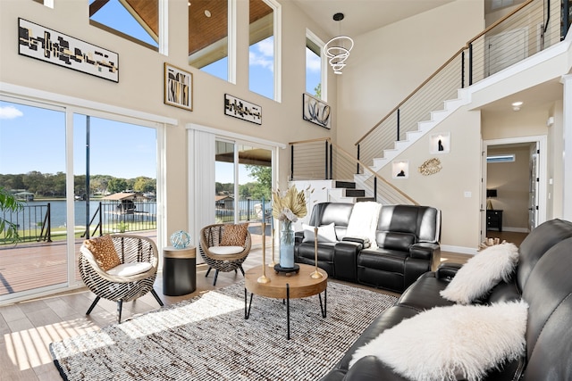 living room with a high ceiling, light wood-type flooring, and a water view