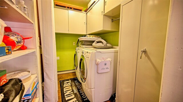 washroom featuring washer and clothes dryer, cabinets, and wood-type flooring