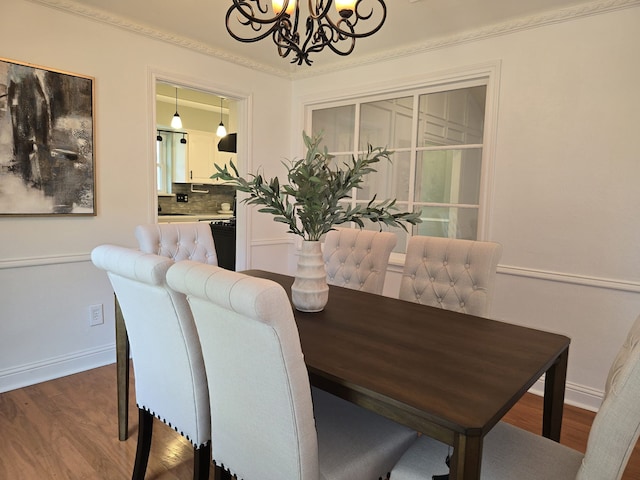 dining room with ornamental molding, wood-type flooring, and a notable chandelier