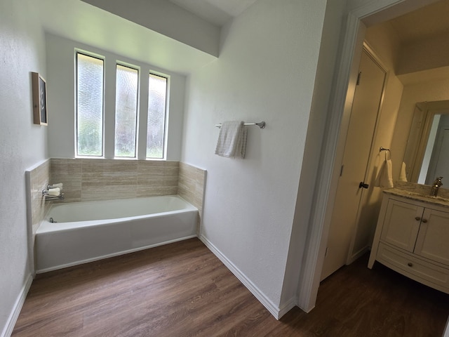 bathroom with a tub, hardwood / wood-style floors, and vanity