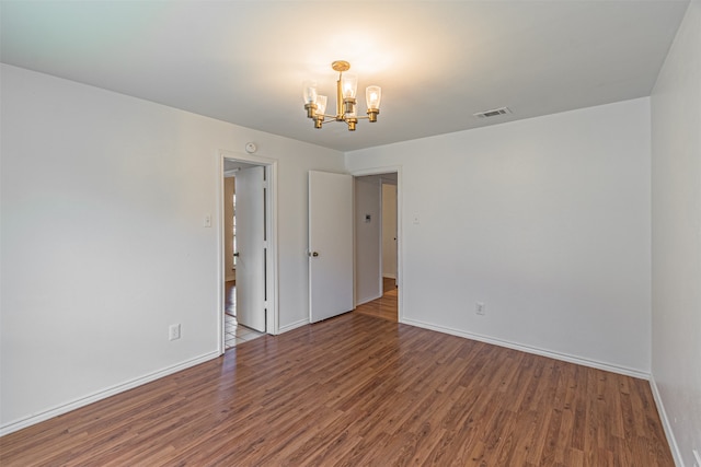 unfurnished room with a notable chandelier and hardwood / wood-style floors