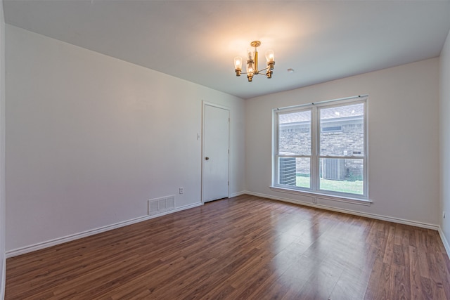 spare room featuring a chandelier and dark hardwood / wood-style floors