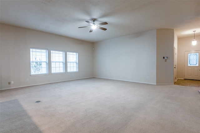 carpeted spare room featuring a wealth of natural light and ceiling fan