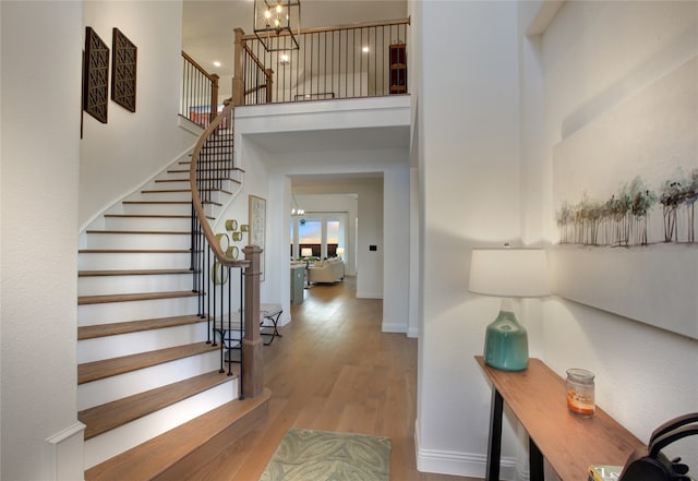 entrance foyer featuring a towering ceiling, light wood-type flooring, and a notable chandelier