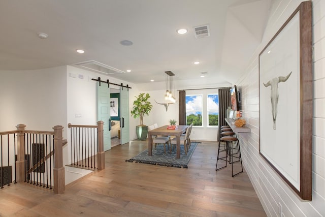 dining space with a barn door and wood-type flooring