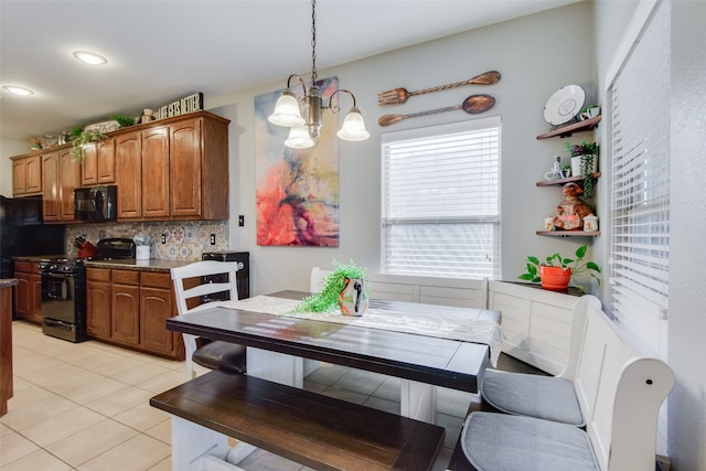 kitchen featuring an inviting chandelier, decorative light fixtures, black appliances, light tile patterned floors, and decorative backsplash