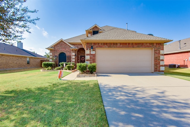 view of front of home with cooling unit, a front yard, and a garage