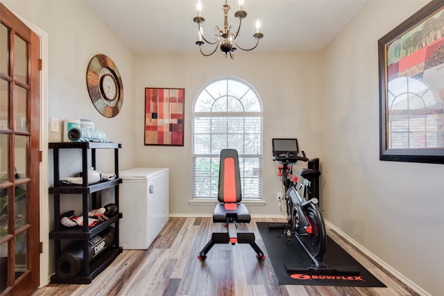 exercise room featuring light hardwood / wood-style flooring, a notable chandelier, and a healthy amount of sunlight