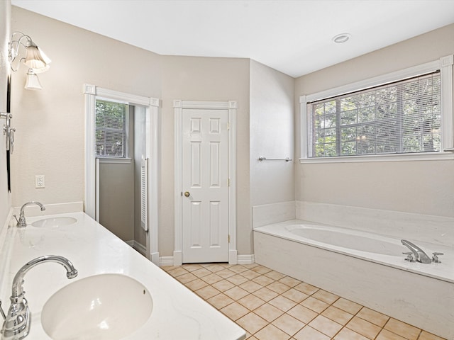 bathroom with tile patterned floors, a washtub, and vanity