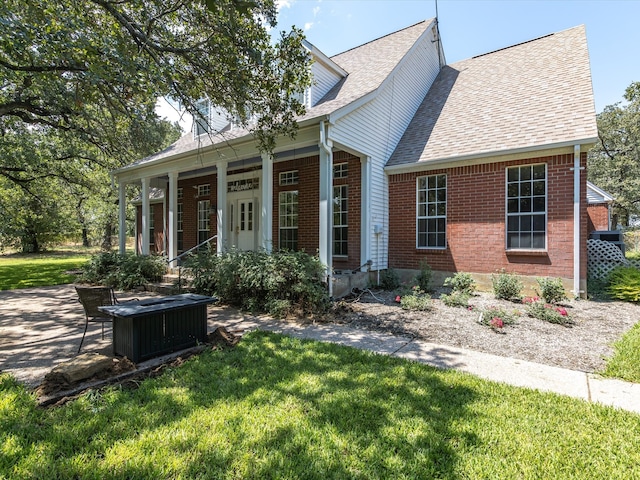 cape cod home with a porch and a front lawn