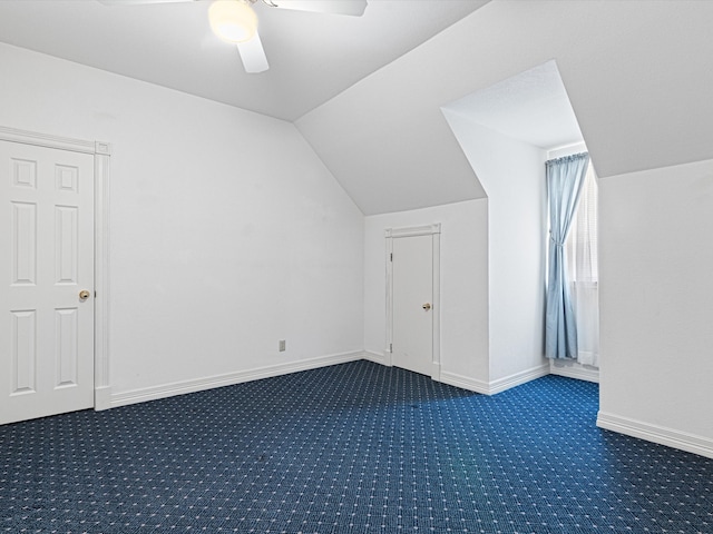 additional living space with ceiling fan, vaulted ceiling, and dark colored carpet