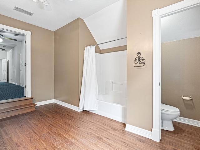 bathroom featuring hardwood / wood-style floors, vaulted ceiling, ceiling fan, toilet, and shower / bathtub combination with curtain