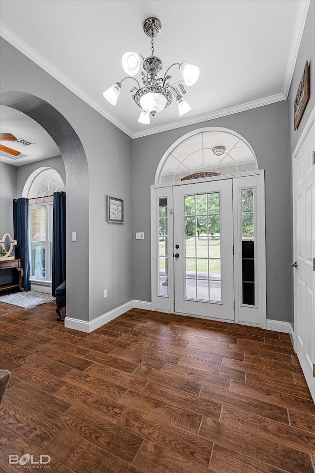 entryway with an inviting chandelier, dark wood-type flooring, and ornamental molding