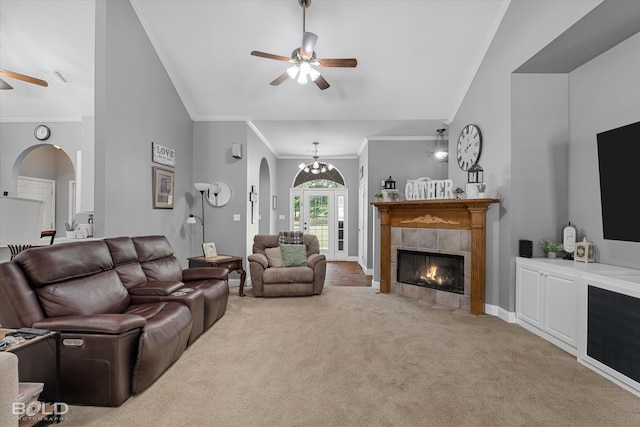 carpeted living room with ceiling fan with notable chandelier, vaulted ceiling, ornamental molding, and a fireplace