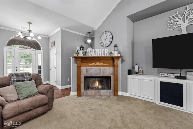 living room with a tile fireplace, ornamental molding, light hardwood / wood-style floors, a notable chandelier, and lofted ceiling