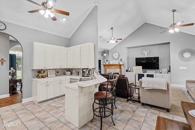 kitchen featuring backsplash, light hardwood / wood-style flooring, kitchen peninsula, ceiling fan, and a breakfast bar