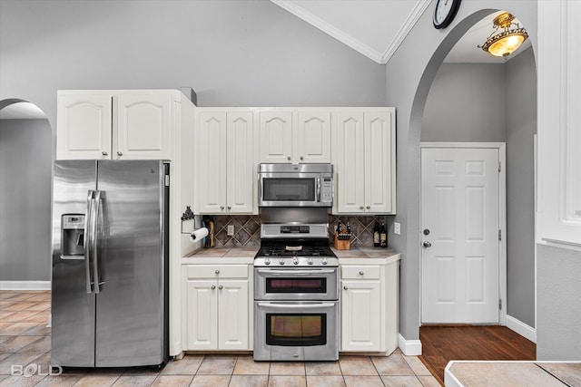 kitchen featuring ornamental molding, light hardwood / wood-style floors, tasteful backsplash, white cabinetry, and stainless steel appliances