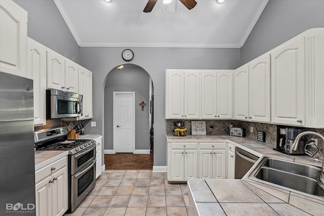 kitchen featuring ceiling fan, light hardwood / wood-style flooring, backsplash, tile countertops, and stainless steel appliances