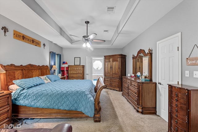 bedroom featuring ceiling fan, carpet floors, and a tray ceiling