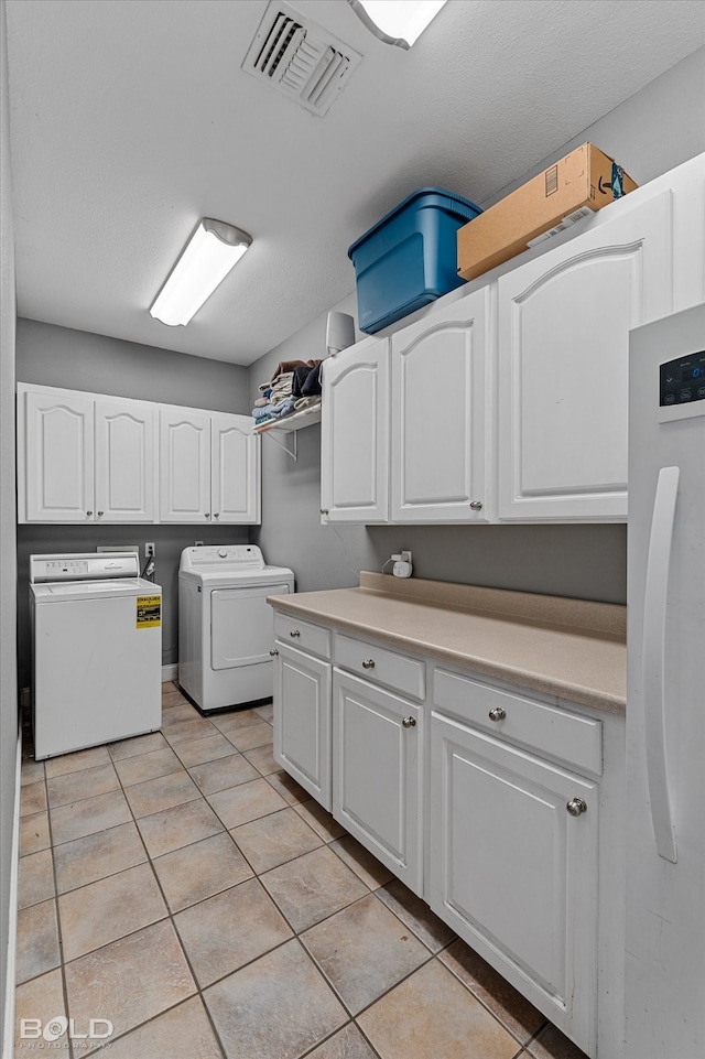 laundry area with light tile patterned flooring, cabinets, and washer and dryer