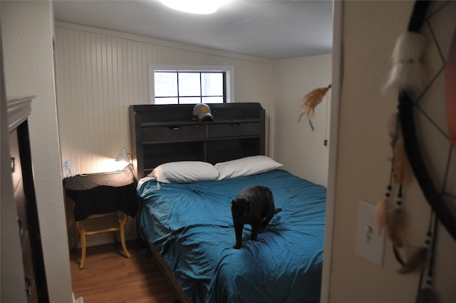 bedroom with wooden walls, lofted ceiling, and hardwood / wood-style flooring