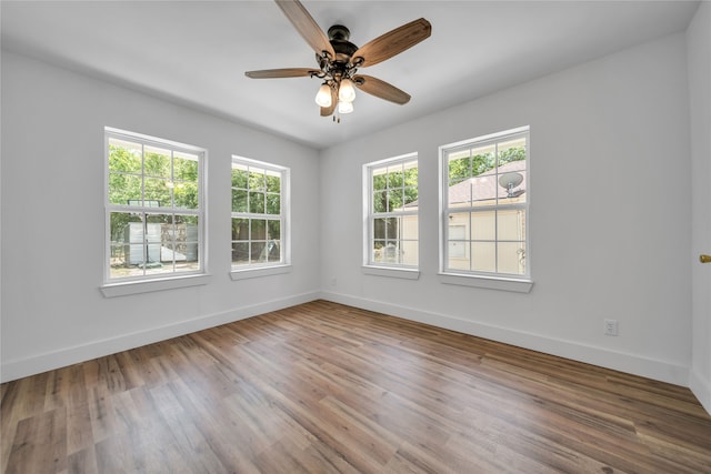 spare room featuring ceiling fan, a wealth of natural light, and wood-type flooring