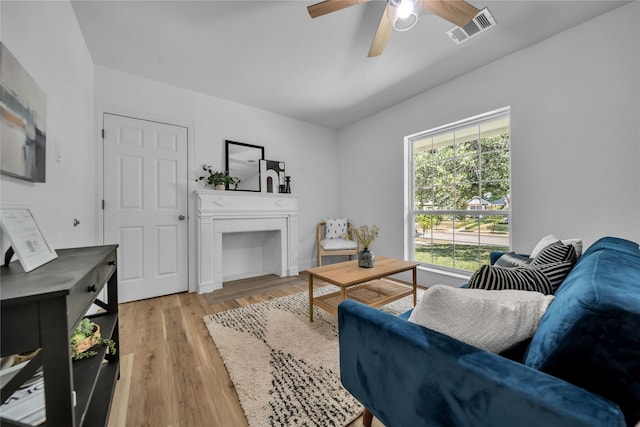 living room with light hardwood / wood-style flooring, ceiling fan, and a fireplace