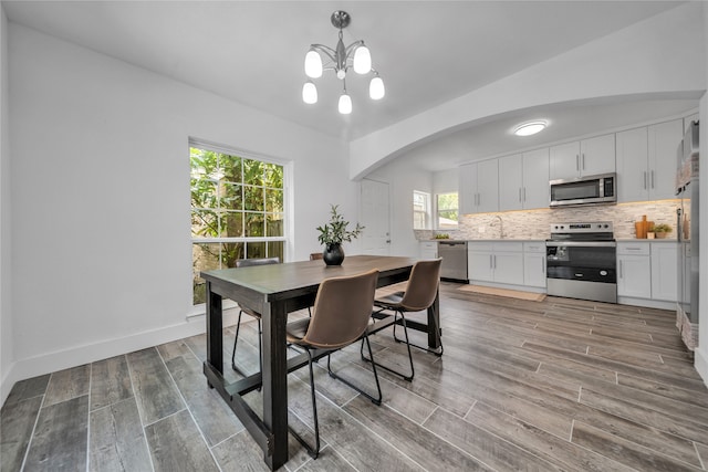 dining area with a notable chandelier, hardwood / wood-style floors, and sink