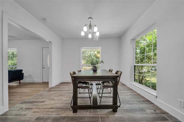 dining space featuring wood-type flooring, an inviting chandelier, and a healthy amount of sunlight