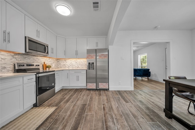 kitchen featuring backsplash, hardwood / wood-style floors, stainless steel appliances, and white cabinets