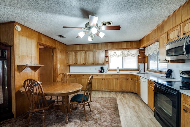 kitchen featuring dishwasher, wooden walls, light wood-type flooring, ceiling fan, and black electric range