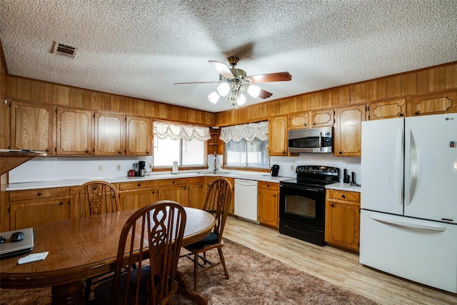 kitchen featuring light hardwood / wood-style flooring, ceiling fan, sink, white appliances, and a textured ceiling